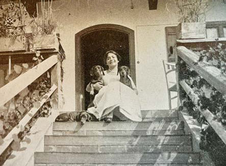 Marion Thoma mit Dackeln vor dem Eingang zum Tuften-Haus
